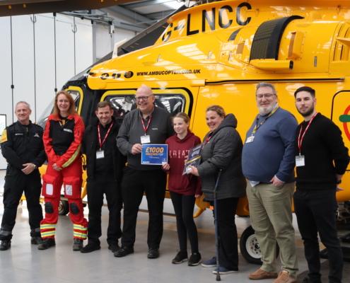 Molly Photographed With Kwik Fit, Lincs & Notts and AAUK team standing next to Helicopter displaying her award.