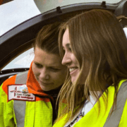 Abi Lewis smiling with Henrietta Davies in the helicopter cockpit.